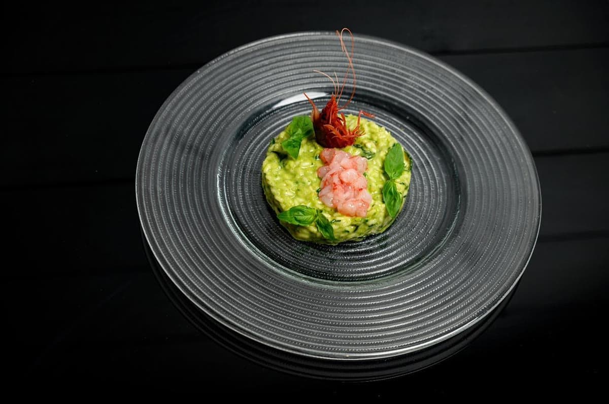 Basil risotto plated with red prawn carpaccio — top-down editorial shot